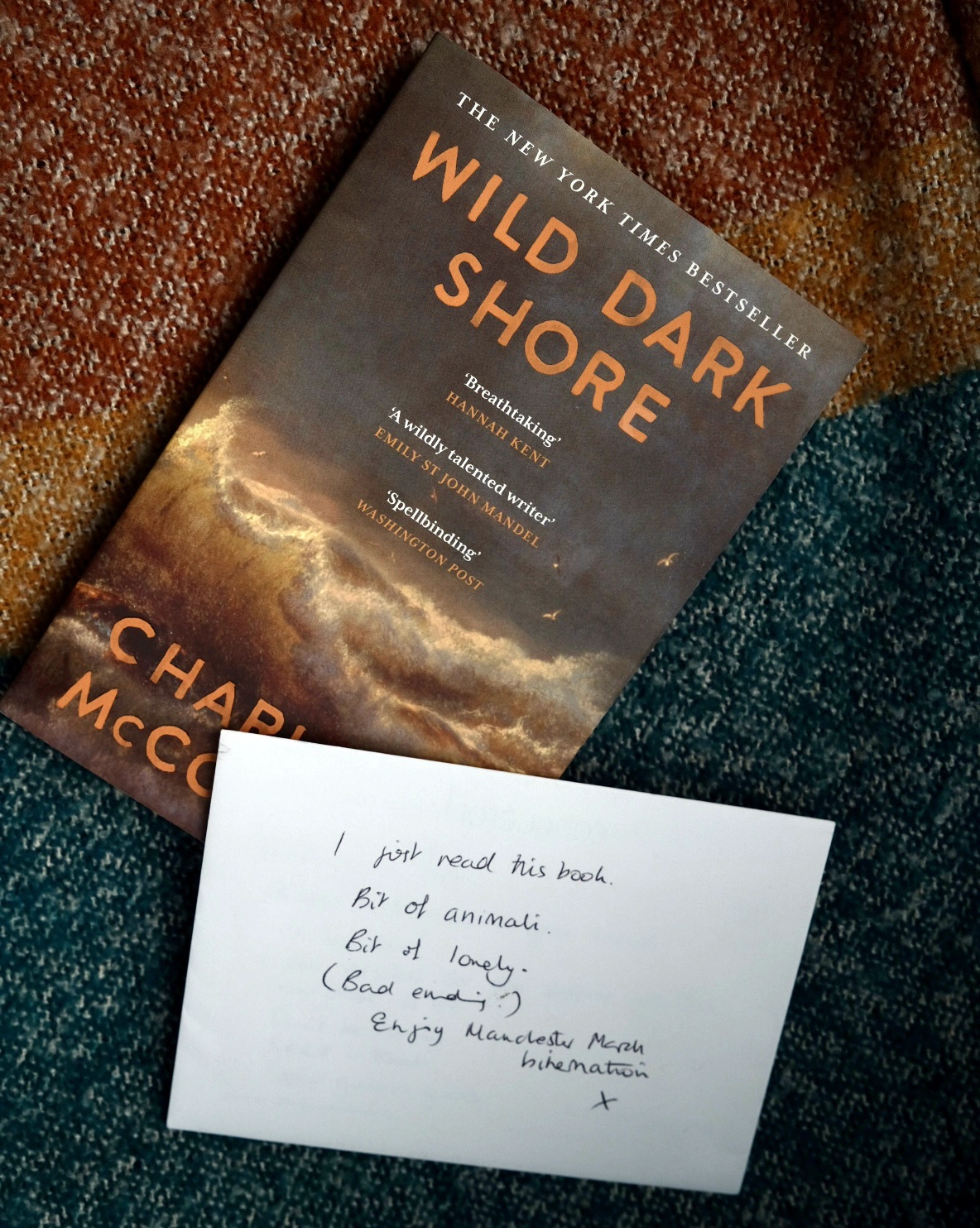 Book on a coloured blanket with an envelop, the front reads: I just read this book, bit of animali. Bit of lovely. (Bad ending) Enjoy Manchester x